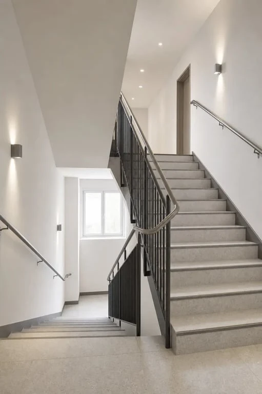 Cage d'escalier immeuble rénovée avec éclairage doux et finitions soignées